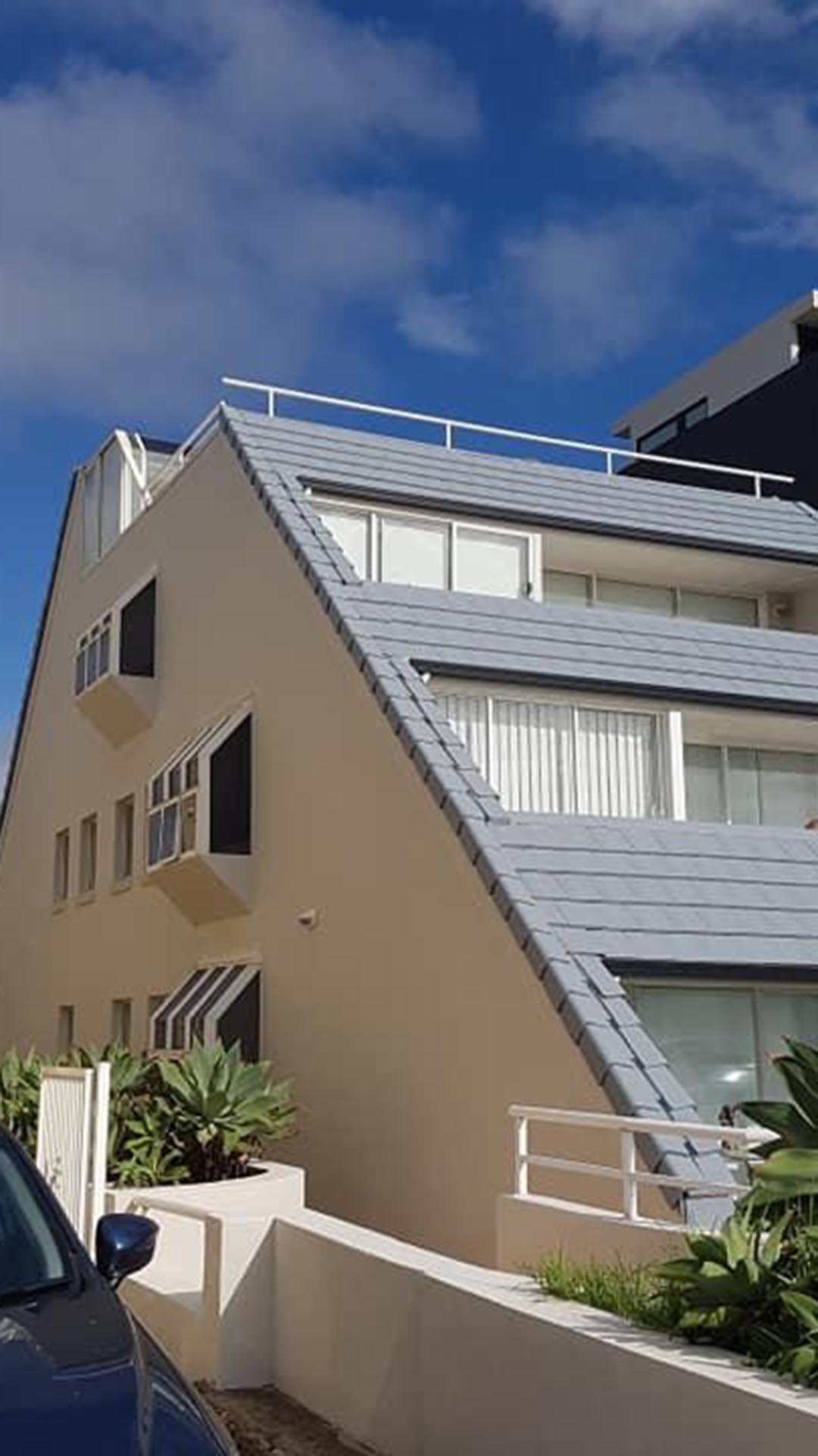 Same cream apartment building with scaffolding removed and grey tiled roof face